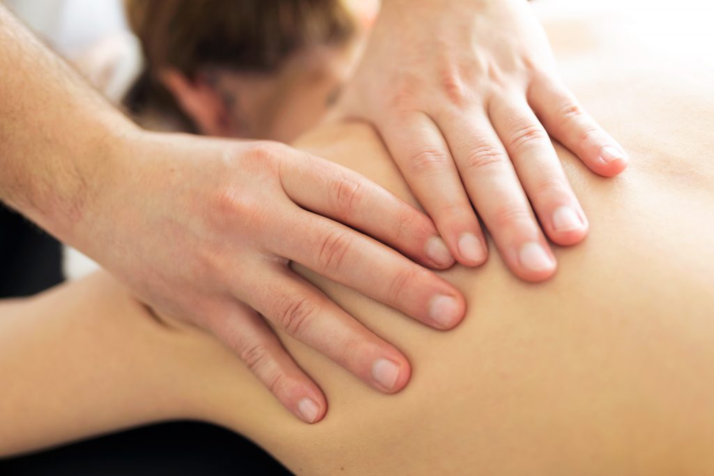 Shot of young physiotherapist doing a back treatment to the patient in a physiotherapy room. Rehabilitation, medical massage and manual therapy concept.